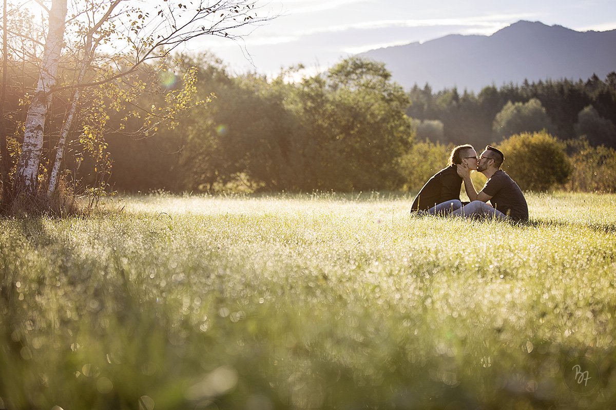 Familienfotografie Bayern: Paar sitzt auf taunasser Wiese