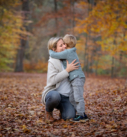 Familienfotografie München: Mutter mit Sohn beim Umarmen im Herbstlaub